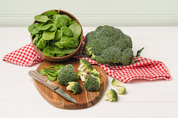 Fresh broccoli with spinach on wooden table close up