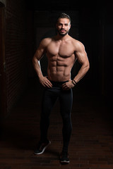 Fototapeta na wymiar Muscular Model Flexing Muscles In Gym