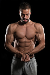 Fototapeta na wymiar Muscular Model Flexing Muscles On Black Background