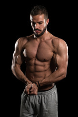 Fototapeta na wymiar Muscular Man Flexing Muscles On Black Background