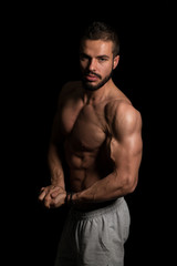 Fototapeta na wymiar Muscular Man Flexing Muscles On Black Background