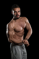 Fototapeta na wymiar Muscular Athlete Flexing Muscles On Black Background