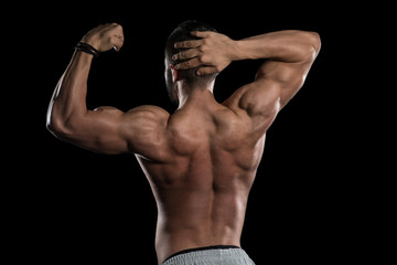Obraz na płótnie Canvas Muscular Model Flexing Muscles On Black Background