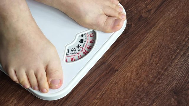 Male feet stepping on bathroom scales. Overweight man standing on weighing machine, about 100 kg. Health care, overload lose weight concept. 4K ProRes HQ codec