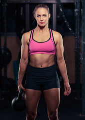 Fototapeta na wymiar Fitness female holding a kettlebell in the gym during a workout