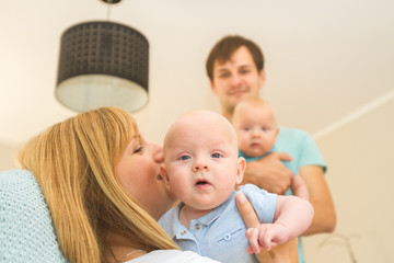 indoor portrait of young beautiful mother and father with baby, family with twins at home