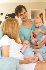 Obraz premium indoor portrait of young beautiful mother and father with baby, family with twins at home