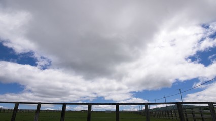 夏の雲と牧場の柵