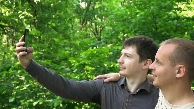 two young men take a selfie in the forest.