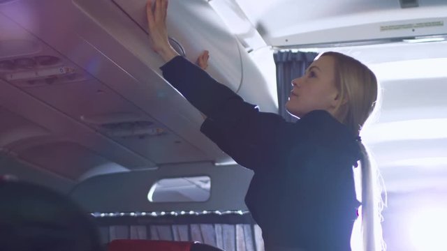 Airplane Stewardess/Flight Attendant Closes Baggage Compartments. Plane is Ready to Take off. Shot on RED EPIC-W 8K Helium Cinema Camera.