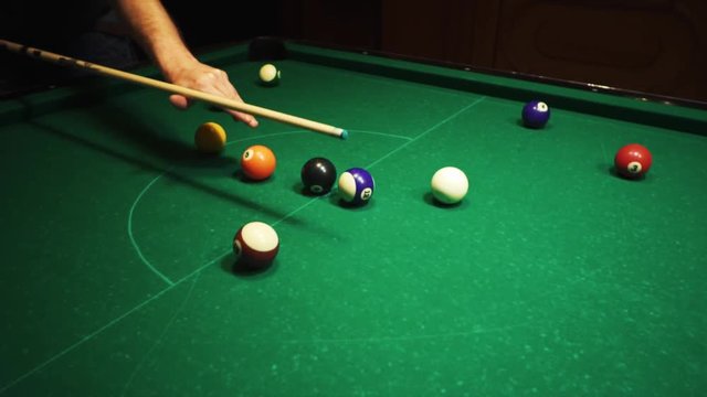 Playing billiards, blowing a cue on the ball, the ball hit the pocket, the ball did not hit the pocket, misfire, hit, American billard, pool, green billiard table, the man plays billiards, breaking