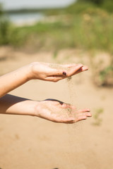 sand running through hands of woman