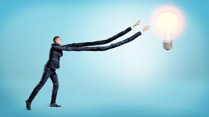 A tiny businessman trying to reach a glowing bulb with his unnaturally elongated arms.