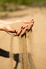 sand running through hands of woman