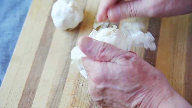 A man rubs off the papery layers of a garlic bulb