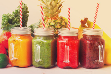 Colorful smoothie drinks with straws in glass jars with igredients close up, retro toned