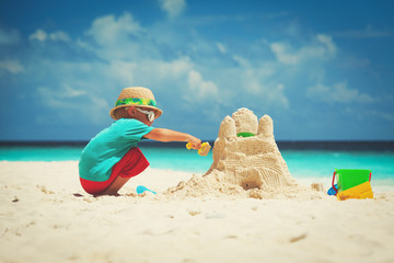 little boy building sand castle on beach