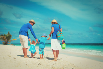 family with little son and daughter walk on beach
