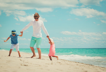 father with little son and daughter play on beach