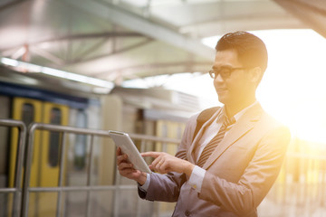 Businesspeople using tablet pc while waiting train at station platform.