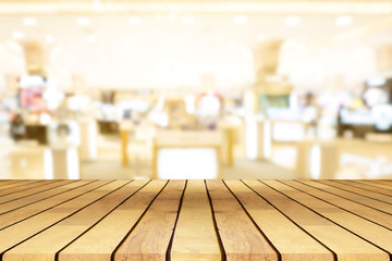 Perspective empty wooden table over blurred shopping mall background, for product display montage or design layout.