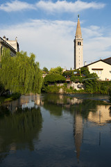 Fototapeta na wymiar The cathedral of San Nicolò is reflected on Livenza river in Sacile. Italy
