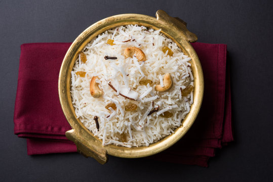coconut rice, coconut sweet rice, also known as narali bhat in marathi, favourite Indian sweet, konkan food, kerala food served in a brass bowl and garnished with cashew, cloves, dry fruits