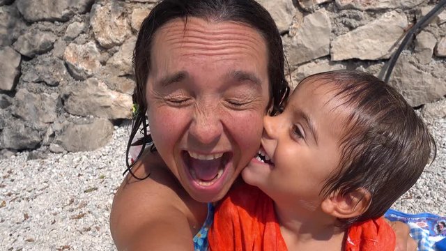 4K Happy mother and son monkey around making selfie on the beach after swim
