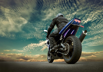 Fototapeta na wymiar Man seat on the motorcycle under sky with clouds
