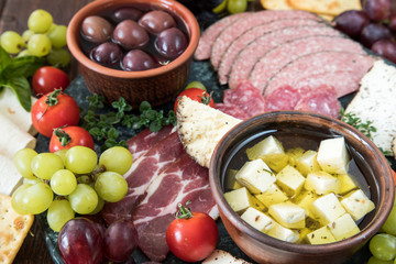 Cheese and meat appetizer selection. Variety of cheese, salami, prosciutto, bread, baguette, grapes, olives