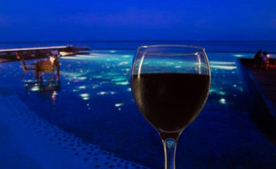 the sea in the background with lights a glass of red wine.