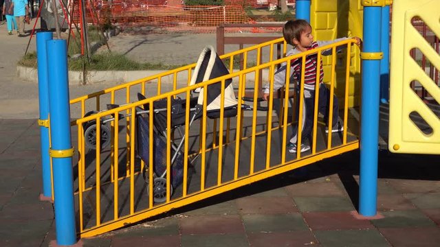 4K Child drags his pushchair up the hill