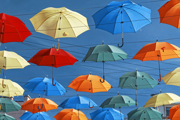 Multi-colored umbrellas in sky above the street. Alley floating umbrellas
