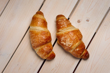 A pair of fresh croissant on the table, top view.