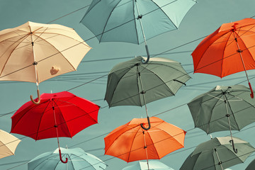 Multi-colored umbrellas in sky above the street. Alley floating umbrellas