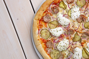 Top view of pizza with sausage, pickled cucumber and mushrooms