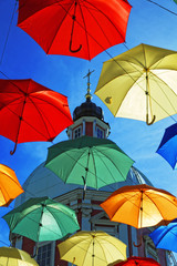 Fototapeta na wymiar Multi-colored umbrellas in sky above the street. Alley floating umbrellas