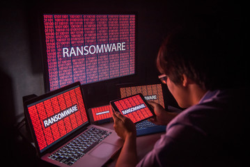 Young Asian male frustrated, confused and headache by ransomware attack on desktop screen, notebook and smartphone, cyber attack and internet security concepts