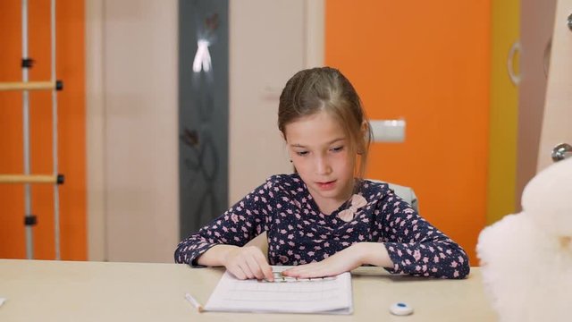 A girl sitting at her desk considers arithmetic examples