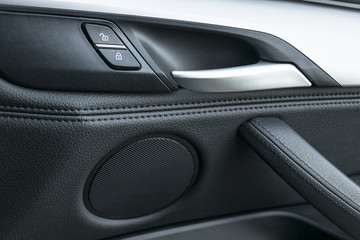 Obraz na płótnie Canvas Car door handle inside the luxury modern car with black leather and switch button control, modern car interior details. Car detailing