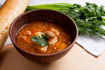 Borsch - traditional Ukrainian and Russian red beetroot soup with red beets in clay bowl on wooden background..
