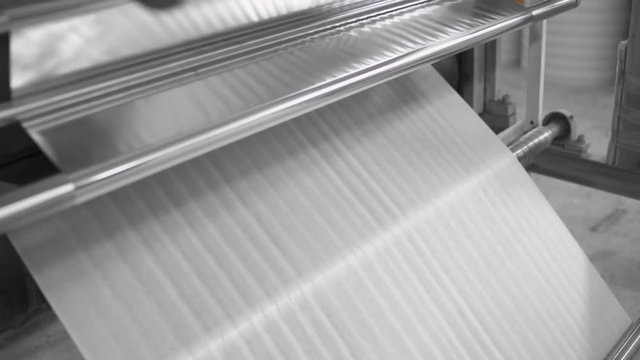 Manufacture of heat-insulating material for pipes, machine rotates roll with thermal insulation foil.
