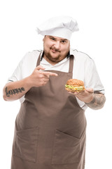 cooker in apron pointing at burger in hand isolated on white