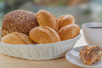 gedeckter Tisch mit Brötchen im Korb und einer Tasse