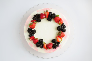Birthday cream cake with strawberries, blueberries and blackberry on white background. Top view. Picture for a menu or a confectionery catalog.