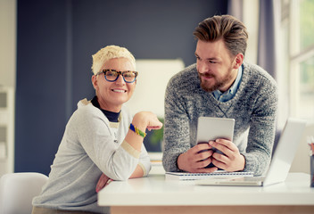 Coworkers using tablet device in modern office