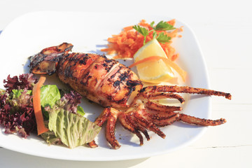Grilled squid served by the sea in Greece, Traditional greek dish on the white wooden table background