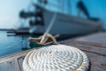 Perfectly coiled rope on the pier with secured yachts on the background