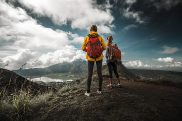 Two hikers stand on a hill and enjoy valley view