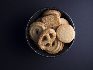 Danish butter cookies with vanilla wreaths (vanillekranse) and sugar pretzels (sukker kringler) in small black bowl isolated on black background